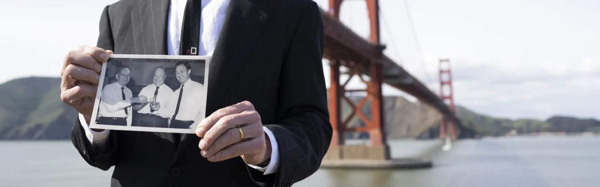 A Global Merchandising leader holding a photo of the founders, with the Golden Gate Bridge behind